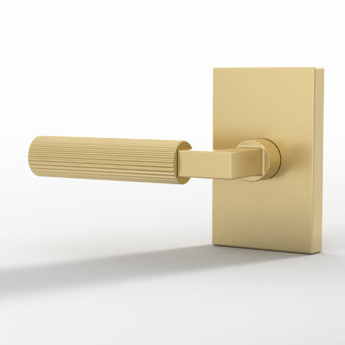 Close-up of a Ridge Satin Brass grooved lever on a rectangular rosette